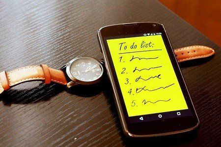 A to do list on a cell phone next to a watch